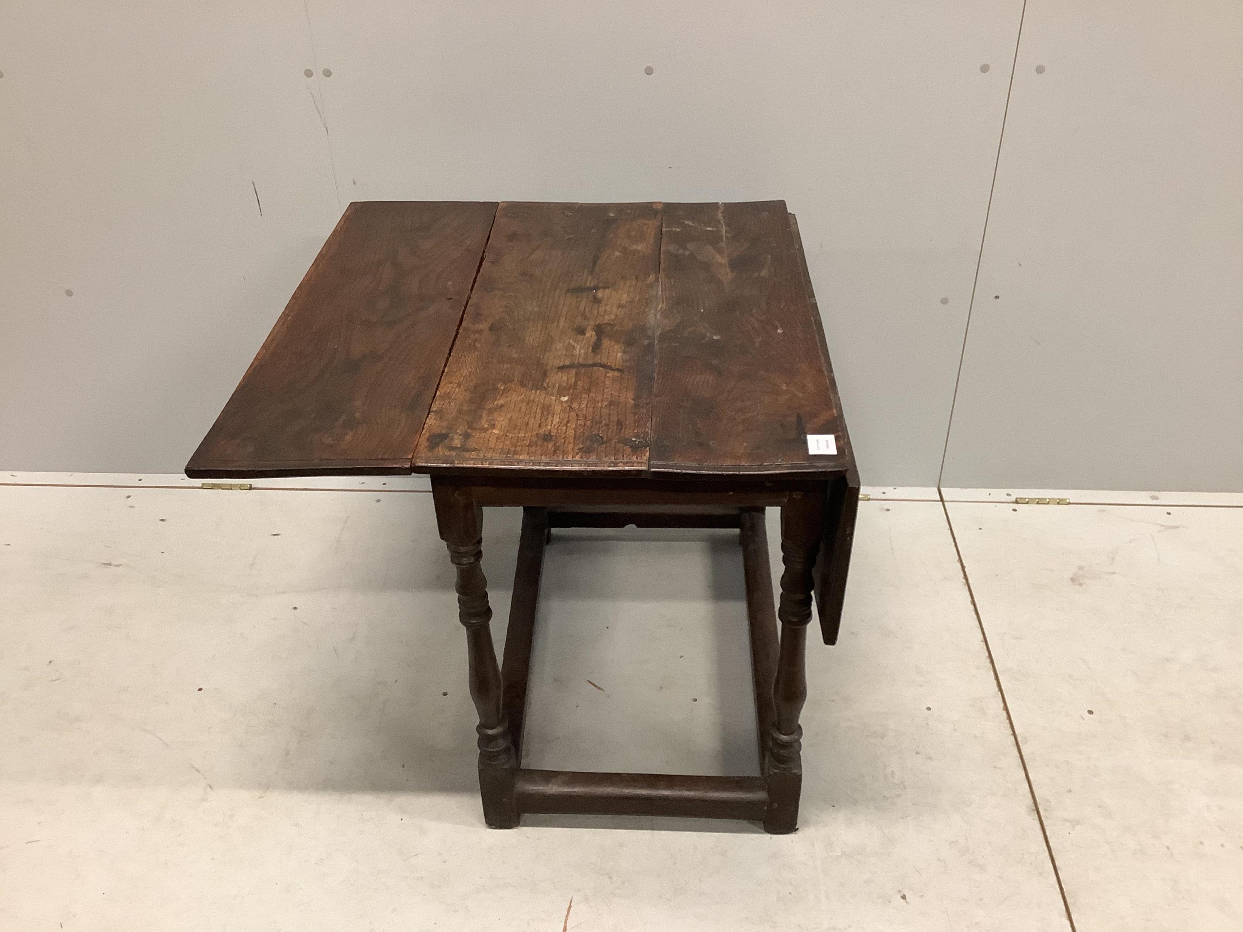 A 17th century rectangular oak drop leaf table on turned legs stretcher rail, label with '165' on the underside and a small white plaque '40', width 82cm, depth 54cm, height 70cm. Condition - poor, one side lacks leaf su